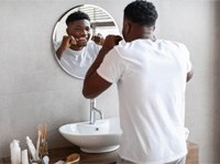 Man smiling while flossing his teeth in bathroom