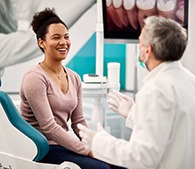 Dentist talking to smiling patient in treatment chair