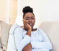 Closeup of woman experiencing toothache on couch