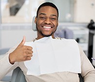 Man smiling while giving thumbs up in treatment chair