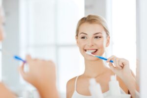 Woman looking in mirror brushing her teeth